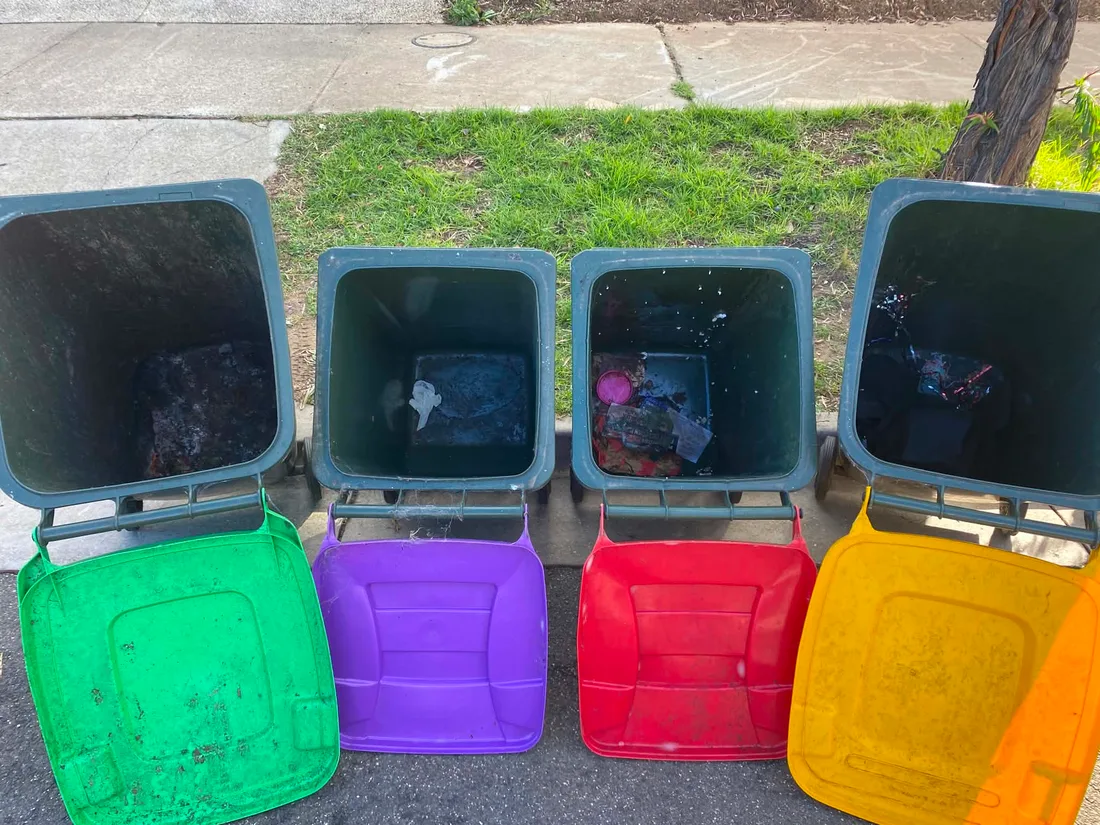 Four wheelie bins dirty inside with leftover waste, before cleaning